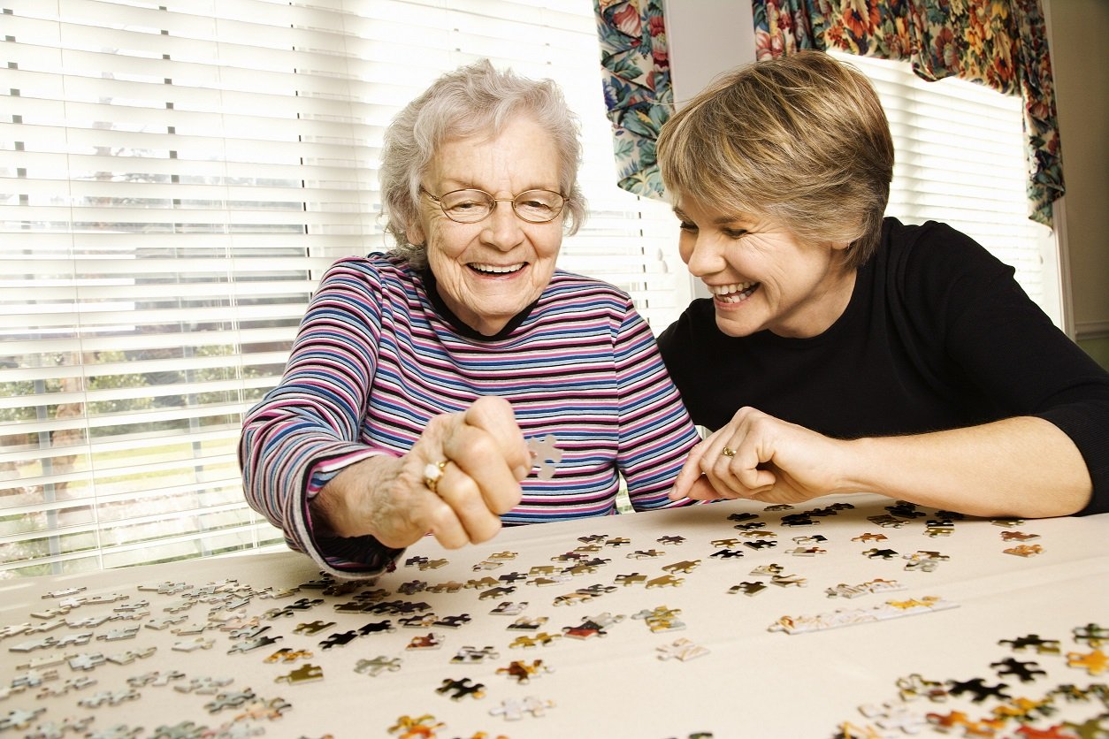 Elderly,Woman,And,A,Younger,Woman,Work,On,A,Jigsaw