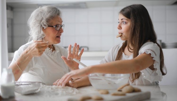 A Senior Woman and A Young Woman Talking Behind a Table