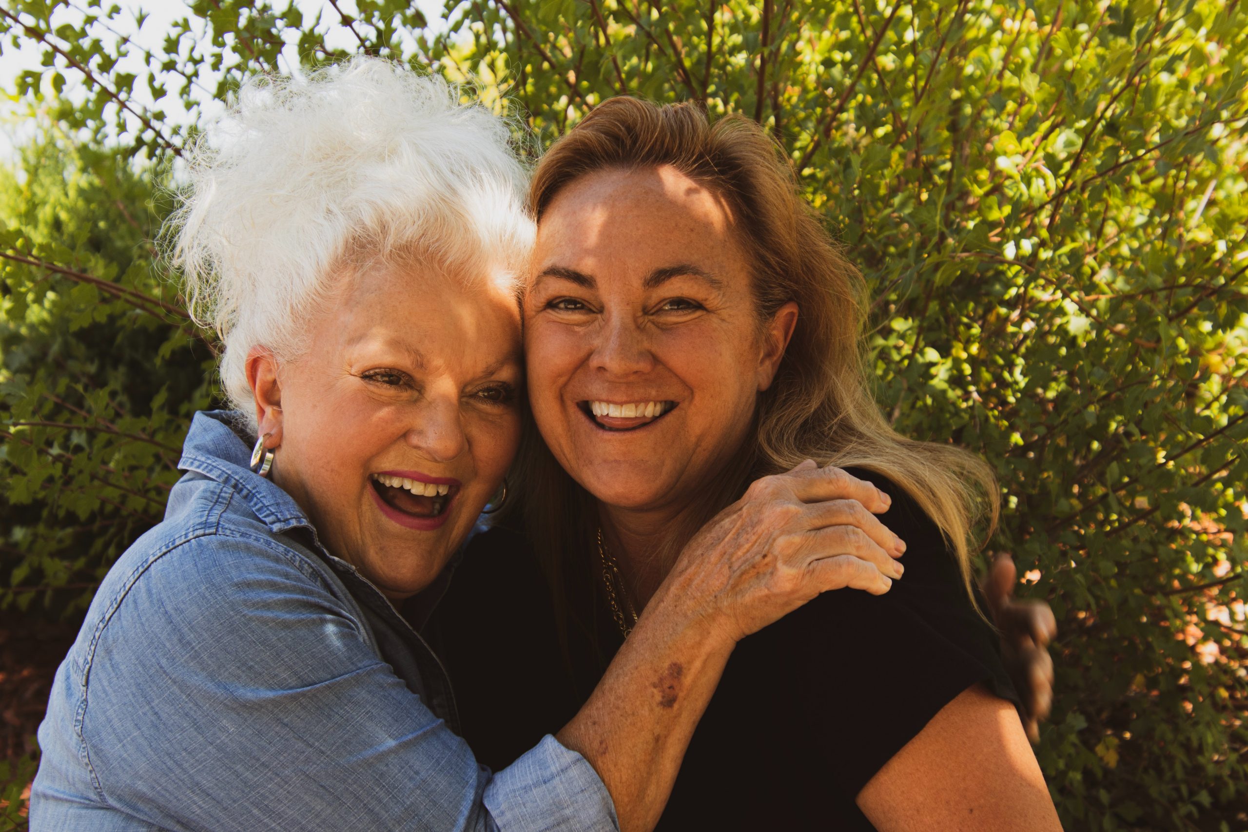 Two older women hugging and laughing.